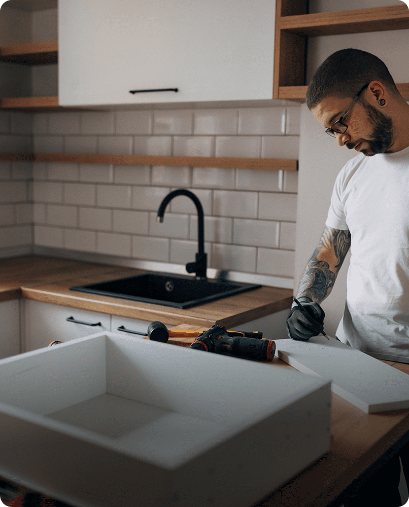 Man assembling furniture in modern kitchen.
